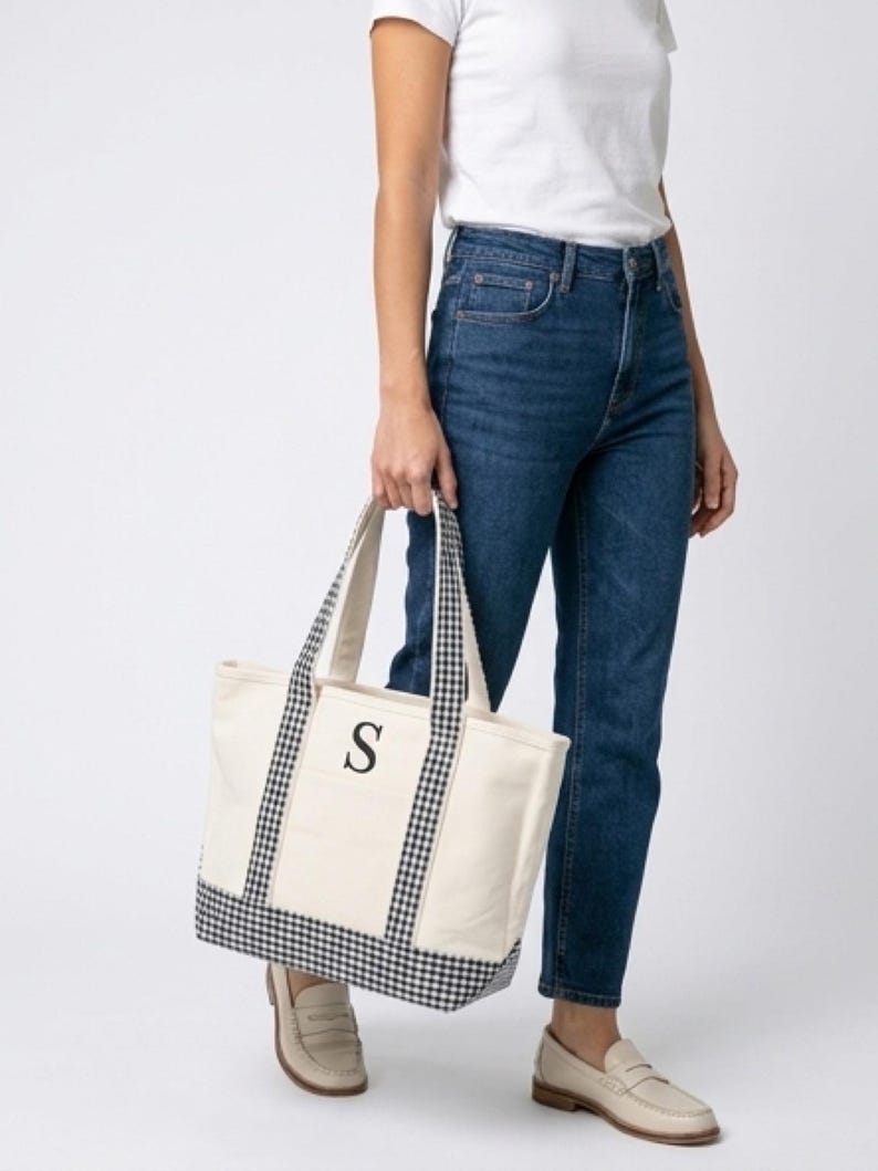 Puede incluir: Bolso tote de lona color crema con detalles de cuadros vichy en blanco y negro. La bolsa presenta una letra "S" negra en la parte delantera. Las asas y el borde inferior son de tela de cuadros vichy. Un accesorio elegante y pr&aacute;ctico.