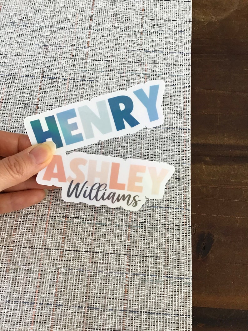May include: Two colorful vinyl stickers with names. The top sticker is blue and green and says "HENRY". The bottom sticker is pink and orange and says "ASHLEY Williams".