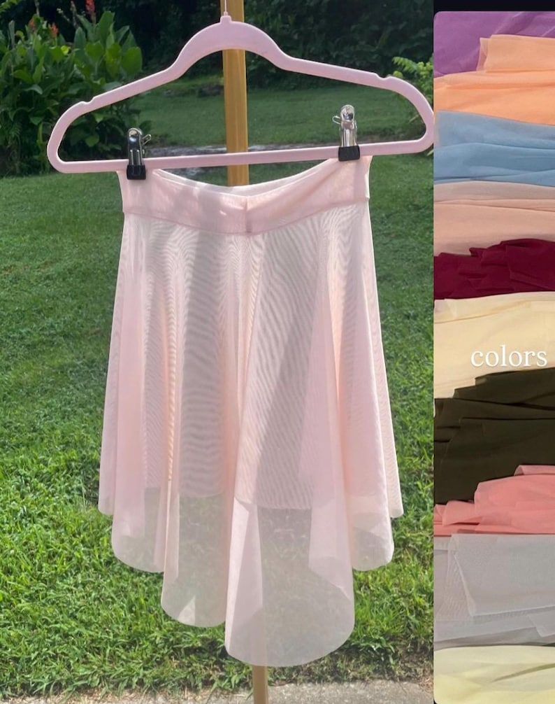 Op de afbeelding: Een lichtroze balletsrok van doorschijnende stof, hangend aan een roze hanger. De rok heeft een gelaagd ontwerp en een zachte, vloeiende uitstraling. Een kleurenkaart met stofstalen is rechts zichtbaar.