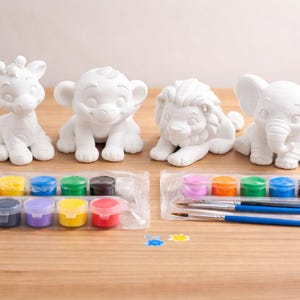 May include: A set of four white ceramic animal figurines: a giraffe, monkey, lion, and elephant. Includes two paint palettes with various colors and two paintbrushes. Ideal for a fun, creative activity.