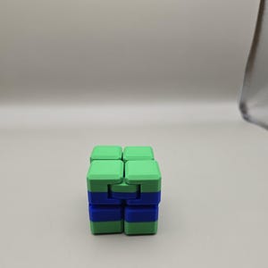 Puede incluir: Un cubo fidget verde y azul. El cubo est&aacute; compuesto por bloques m&aacute;s peque&ntilde;os y conectados que se pueden manipular y girar. La combinaci&oacute;n de colores es una combinaci&oacute;n de verde claro y azul, creando un contraste visualmente atractivo. El juguete est&aacute; dise&ntilde;ado para aliviar el estr&eacute;s y la estimulaci&oacute;n sensorial.