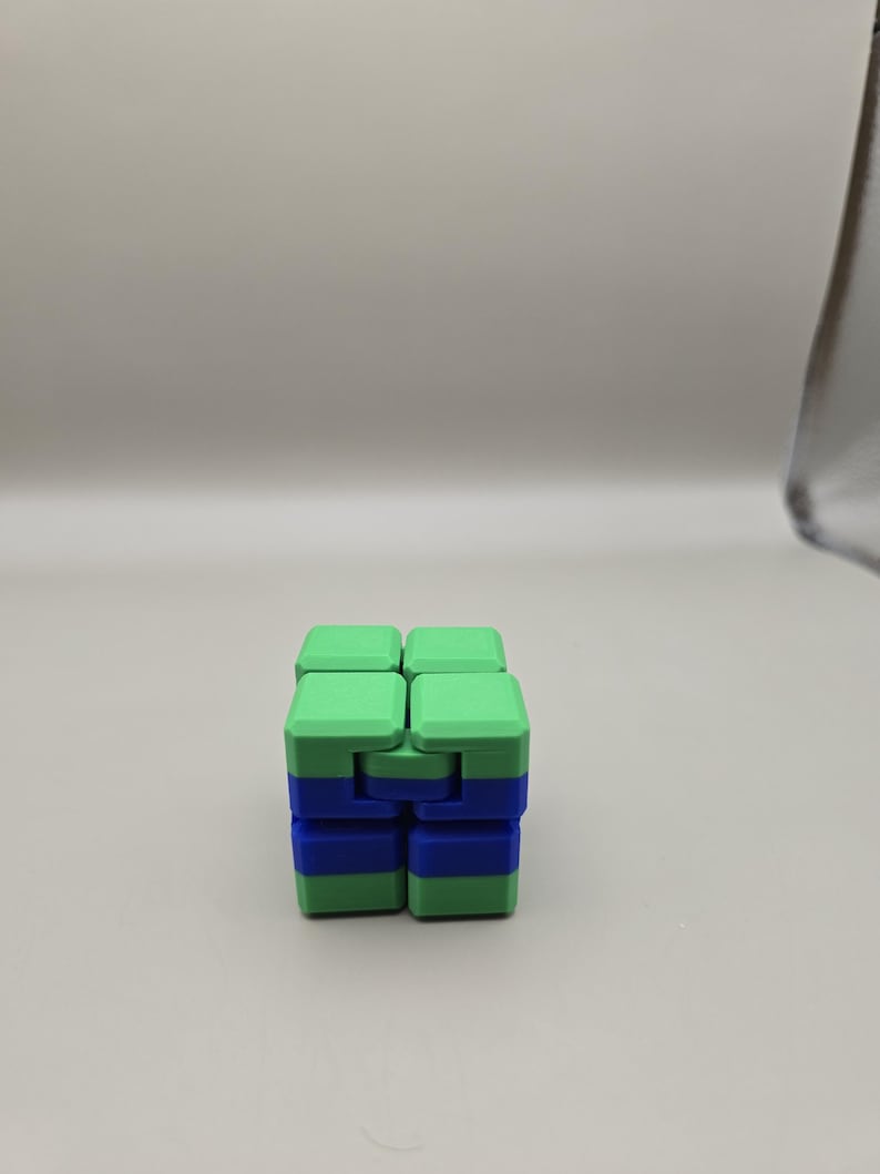 Puede incluir: Un cubo fidget verde y azul. El cubo est&aacute; compuesto por bloques m&aacute;s peque&ntilde;os y conectados que se pueden manipular y girar. La combinaci&oacute;n de colores es una combinaci&oacute;n de verde claro y azul, creando un contraste visualmente atractivo. El juguete est&aacute; dise&ntilde;ado para aliviar el estr&eacute;s y la estimulaci&oacute;n sensorial.
