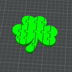 Op de afbeelding: Een heldergroene klaver met een driebladig ontwerp. De klaver is gesegmenteerd met een rasterpatroon op de achtergrond. De afbeelding is een digitale weergave van het St. Patrick's Day-symbool.