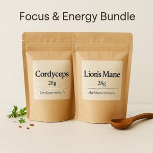 Könnte beinhalten: Zwei braune Papiertüten mit den Aufschriften "Cordyceps" und "Lion's Mane", die jeweils 28g enthalten. Der Text "Focus & Energy Bundle" steht oben. Ein Holzlöffel und Grünzeug sind ebenfalls zu sehen.
