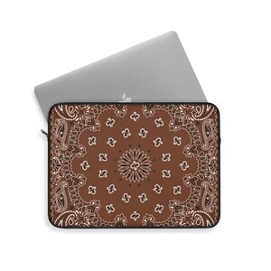 May include: Brown laptop sleeve with a white and black paisley pattern.