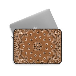 May include: A brown laptop sleeve with a black and white paisley pattern. The sleeve has a zipper closure.