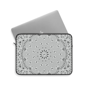 May include: A gray laptop sleeve with a black and white paisley pattern. The sleeve is designed to protect a laptop from scratches and bumps.