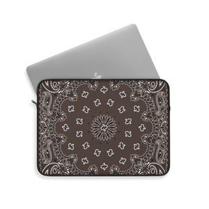 May include: A brown laptop sleeve with a white paisley pattern. The sleeve has a zipper closure.