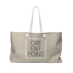 May include: A beige canvas tote bag with white rope handles and a white frame around the text "ORIENT POINT" in black.