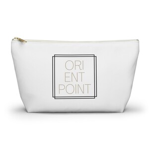 May include: White canvas zippered pouch with a black and white frame around the text "ORIENT POINT" in beige.