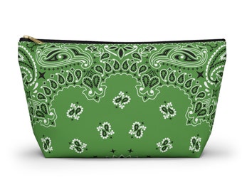 Puede incluir: Un estuche verde con cremallera que presenta un patrón de bandana de cachemira en blanco y negro. El accesorio tiene una forma cónica con un cierre de cremallera negro en la parte superior, mostrando un motivo floral y de gota repetido.