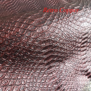 May include: Close-up of a textured, metallic, copper-coloured material with a scale-like pattern. The words "Retro Copper" are printed in red. The material has a shiny, reflective surface.