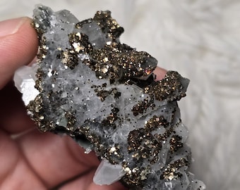 May include: A cluster of clear quartz crystals with a coating of gold pyrite. The crystals are sharp and pointed, and the pyrite is a metallic gold color.