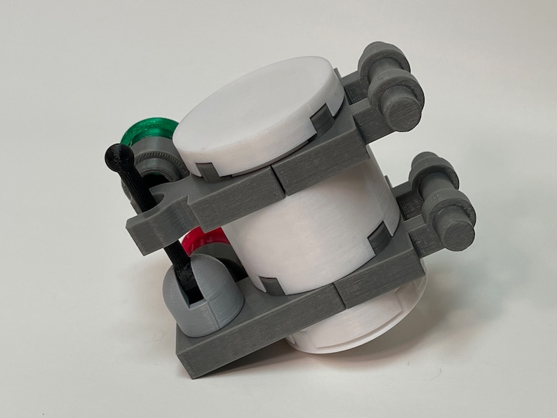 May include: A 3D-printed model of a machine, featuring a white cylindrical body, gray structural components, and accents of black, green, and red. The design includes a lever and several rounded protrusions, suggesting a mechanical or industrial theme.