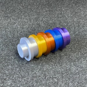 May include: A collection of six colorful, cylindrical objects in a row. The colors include silver, yellow, orange, blue, and purple. Each object has a flat, circular base and a smaller, raised cylinder on top.