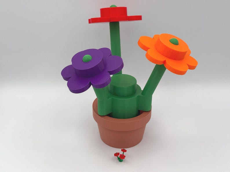 Puede incluir: Un arreglo floral caprichoso en una maceta de terracota. Las flores son rojas, naranjas y moradas con tallos y centros verdes. Un peque&ntilde;o grupo de flores rojas se encuentra en la base.