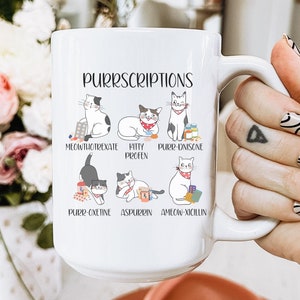 May include: White ceramic mug with a black outline of a cat holding pills and the text "PURRSCRIPTIONS" with the names of cat-themed medications below each cat.