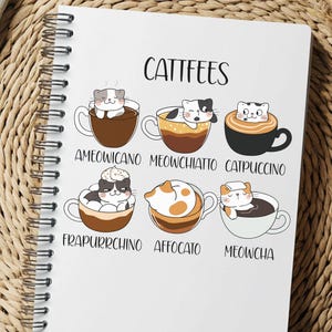 Può includere: Un quaderno a spirale bianco con la scritta "CATTEES" in alto. Il quaderno presenta illustrazioni di gatti in tazze di caffè, con nomi come "Ameowicano" e "Catpuccino" sotto ogni immagine. Il quaderno è su una superficie tessuta.