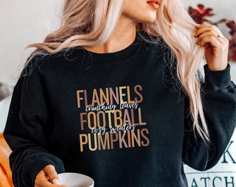 May include: Black sweatshirt with a graphic print that reads "Flannels, crunching leaves, football, cozy sweaters, pumpkins".