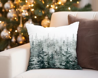 May include: A white throw pillow with a watercolor design of a forest with green trees and a foggy background.