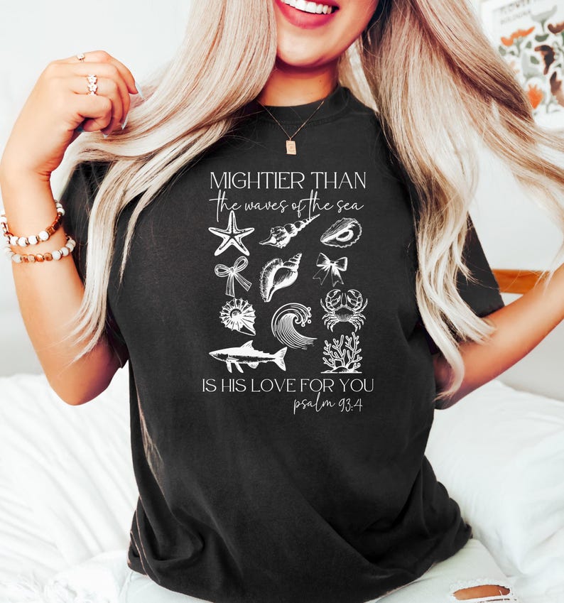 May include: Black t-shirt with white graphic of various sea creatures and the text "Mightier than the waves of the sea. Is His love for you. Psalm 93:4". The design includes a starfish, shells, and a crab.