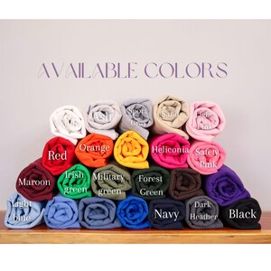 K&ouml;nnte beinhalten: Eine Sammlung gerollter Stoffmuster in verschiedenen Farben mit der Aufschrift AVAILABLE COLORS, darunter Wei&szlig;, Asche, Sportgrau, Sand, Hellrosa, Rot, Orange, Heliconia, Sicherheitsprosa, Kastanienbraun, Irischgr&uuml;n, Milit&auml;rgr&uuml;n, Waldgr&uuml;n, Marine und Schwarz.