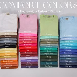 May include: Stacks of folded heavyweight unisex t-shirts in various colors, including white, pink, green, and blue. The image displays a color chart with names like "Blossom," "Chambray," and "True Navy."