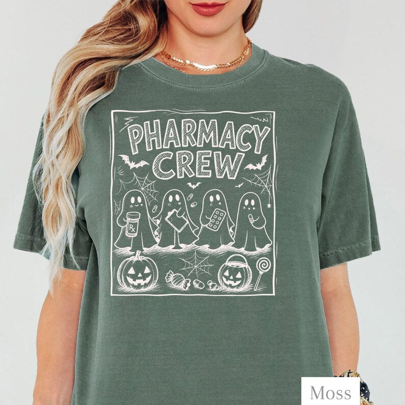 K&ouml;nnte beinhalten: Ein moosgr&uuml;nes Kurzarm-T-Shirt mit einem wei&szlig;en Grafikdruck von vier Geistern und dem Text PHARMACY CREW. Das Design enth&auml;lt Illustrationen einer Medikamentendose, eines Klemmbretts, einer Pillenpackung, eines K&uuml;rbisses und eines Lollis.