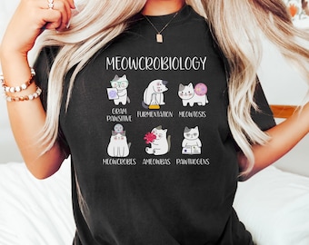 May include: A black t-shirt with the text "MEOWCROBIOLOGY" and illustrations of cats representing different aspects of microbiology, including "Gram Pawsitive", "Fermentation", "Meowtosis", "Meowcrobes", "Ameowbas", and "Pawthogens".
