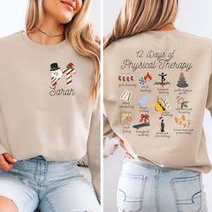 May include: Beige sweatshirt with a snowman and candy cane graphic, the name "Sarah" is below. The back of the sweatshirt has the text "12 Days of Physical Therapy" with illustrations of physical therapy exercises.