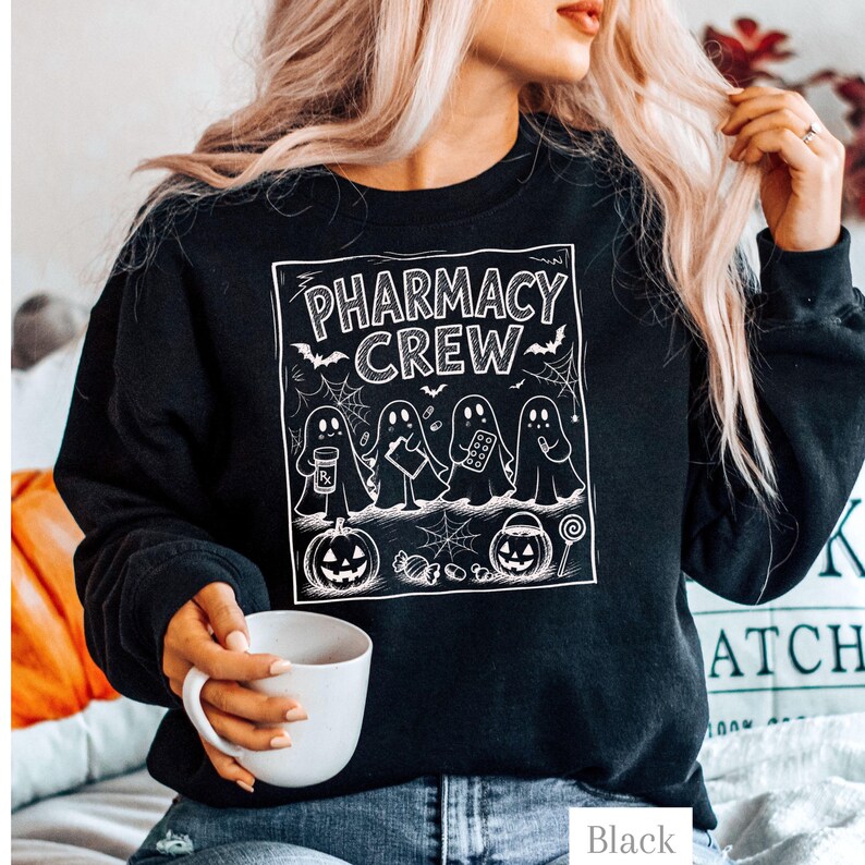 K&ouml;nnte beinhalten: Ein schwarzes Langarm-Sweatshirt mit einem wei&szlig;en Grafikdruck von vier Geistern. Der Text lautet PHARMACY CREW. Die Geister sind mit einer Medikamentenflasche, einem Klemmbrett, einer Pillenpackung und einem Stift dargestellt, erg&auml;nzt durch K&uuml;rbisse.