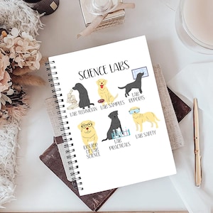 May include: A spiral-bound notebook with the words "SCIENCE LABS" at the top. The notebook features illustrations of lab-themed dogs, including a dog with glasses labeled "DOCTOR OF LAB SCIENCE."