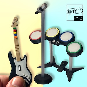 May include: A black electric guitar with a white pickguard and a brown neck with colorful fret markers. A microphone stand with a microphone and a drum set with four drums and a foot pedal. The drums are black with colored rings around the edges. The drums are on a stand with a black base.