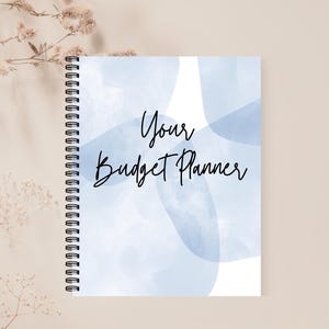 May include: A blue and white spiral bound notebook with the text "Your Budget Planner" on the front cover.