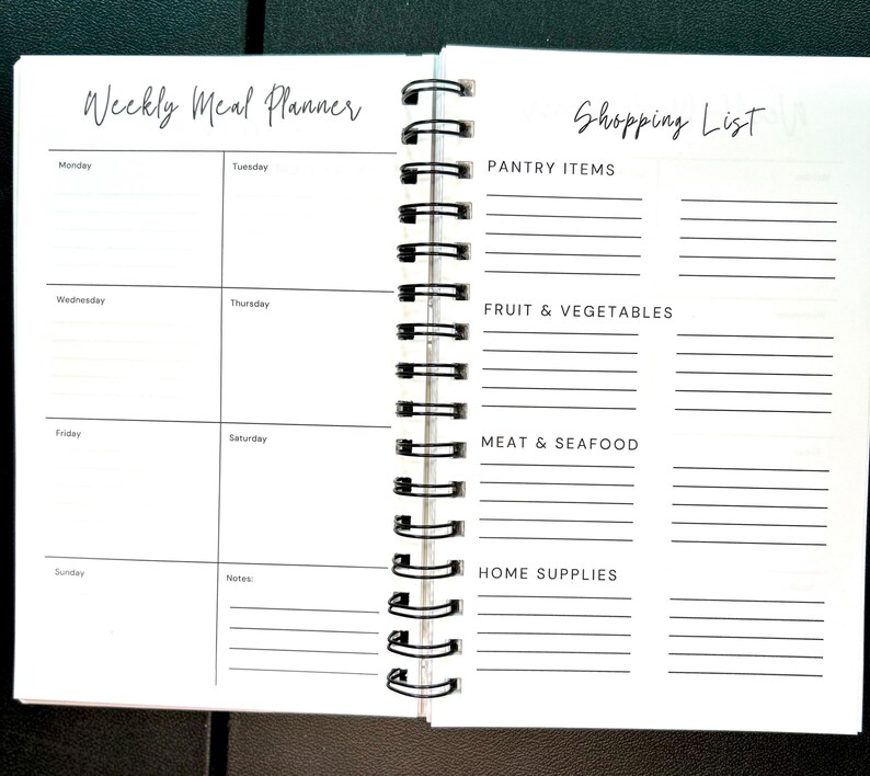 May include: A spiral-bound planner open to two pages. The left page is titled Weekly Meal Planner with sections for Monday through Sunday and a notes area. The right page is titled Shopping List with categories for Pantry Items, Fruit & Vegetables, Meat & Seafood, and Home Supplies.