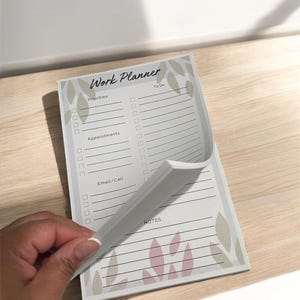 May include: A white work planner with a floral design. The planner has sections for priorities, appointments, email/call, and notes.