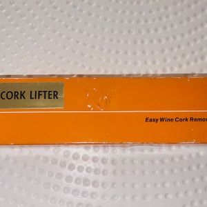 May include: A white ceramic mug with a black handle and the text "But First, Coffee" in a black, handwritten-style font. The mug is on a white surface.