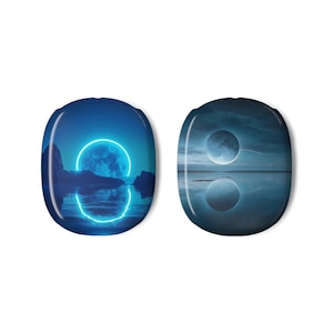 Puede incluir: Dos objetos decorativos ovalados con temática celestial. Uno presenta una luna azul con un anillo de neón, montañas y agua. El otro muestra una luna reflejada en el agua bajo un cielo estrellado. Ambos tienen un acabado brillante.