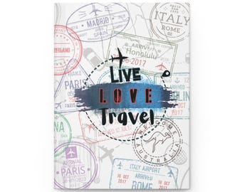 May include: A white journal with a travel theme. The cover features travel stamps from various cities, including Paris, Rome, and Madrid. The words "LIVE LOVE TRAVEL" are prominently displayed in the center, with a blue and red color scheme.