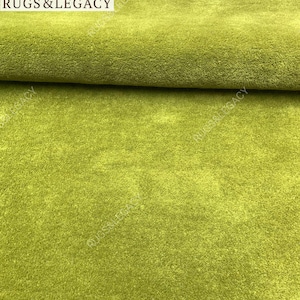 Close-up texture of hand-tufted green wool area rug showing soft plush pile and rich solid green color
