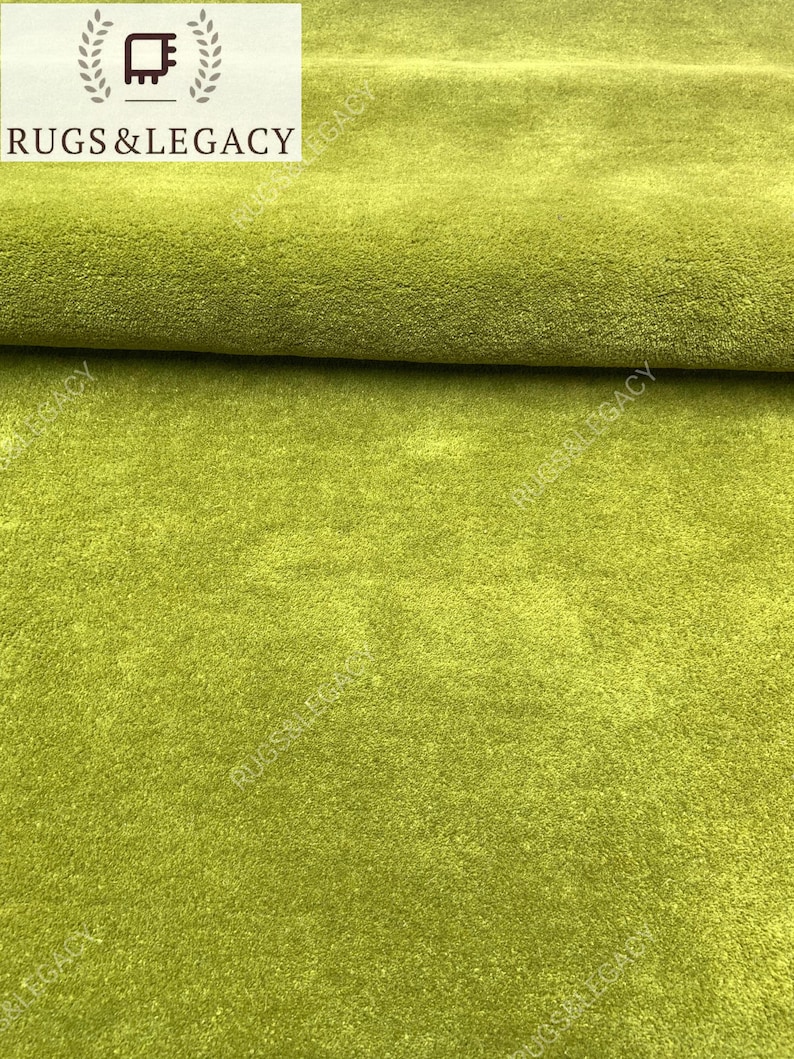 Close-up texture of hand-tufted green wool area rug showing soft plush pile and rich solid green color
