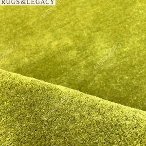 Close-up texture of hand-tufted green wool area rug showing soft plush pile and rich solid green color