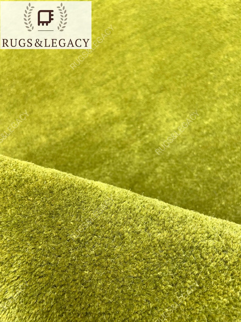 Close-up texture of hand-tufted green wool area rug showing soft plush pile and rich solid green color