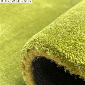 Close-up texture of hand-tufted green wool area rug showing soft plush pile and rich solid green color