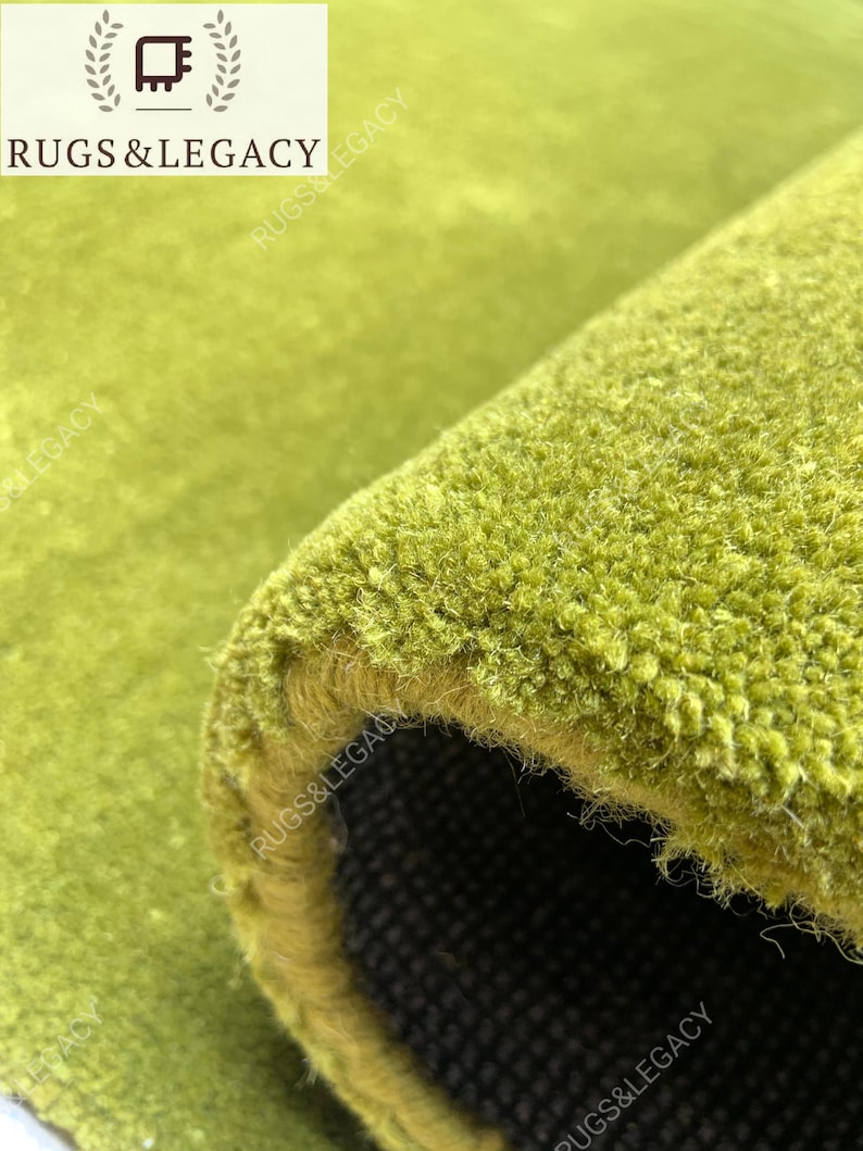 Close-up texture of hand-tufted green wool area rug showing soft plush pile and rich solid green color