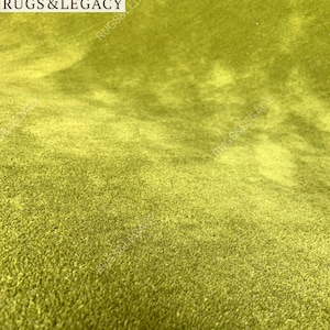 Macro close-up of soft wool fibers on green hand-tufted area rug highlighting luxurious texture and color depth.
