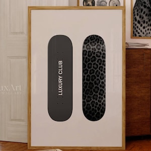 May include: A framed print featuring two skateboard designs. One is solid black with "LUXURY CLUB" text, the other has a leopard print pattern. The artwork is displayed in a room with other framed art.