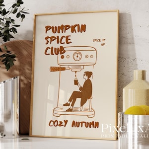 Puede incluir: Un estampado enmarcado con un fondo beige e ilustraciones marrones. El texto dice "Pumpkin Spice Club" y "Cozy Autumn". La ilustración representa a una persona sentada en un taburete, sosteniendo una taza y una máquina de espresso.
