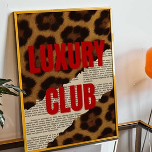 May include: Framed art print with a gold frame. The artwork features a leopard print design with the words "LUXURY CLUB" in bold red letters. The background includes torn paper with text.