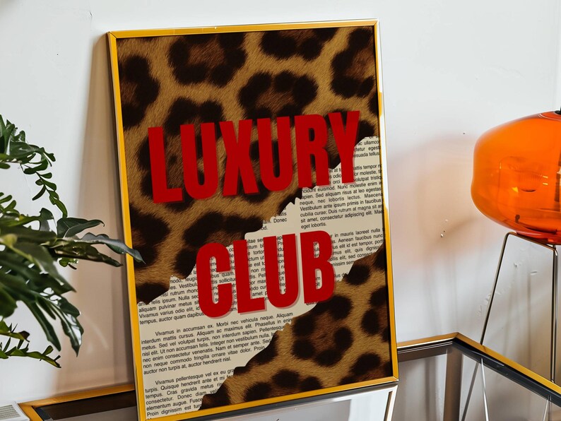 May include: Framed art print with a gold frame. The artwork features a leopard print design with the words "LUXURY CLUB" in bold red letters. The background includes torn paper with text.